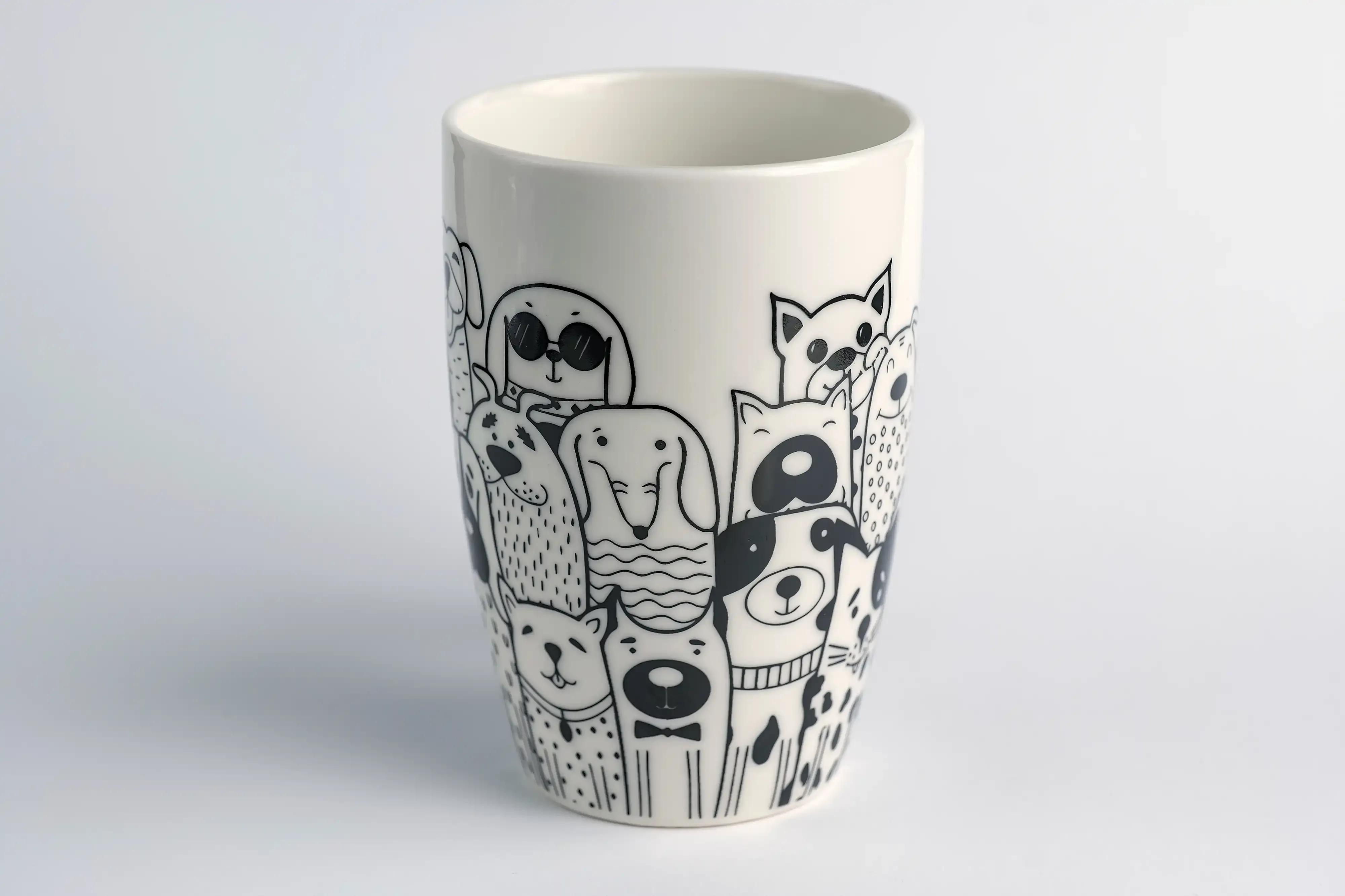 Fotografia de produto de uma caneca branca com uma ilustração de diversos cães em toda a volta.